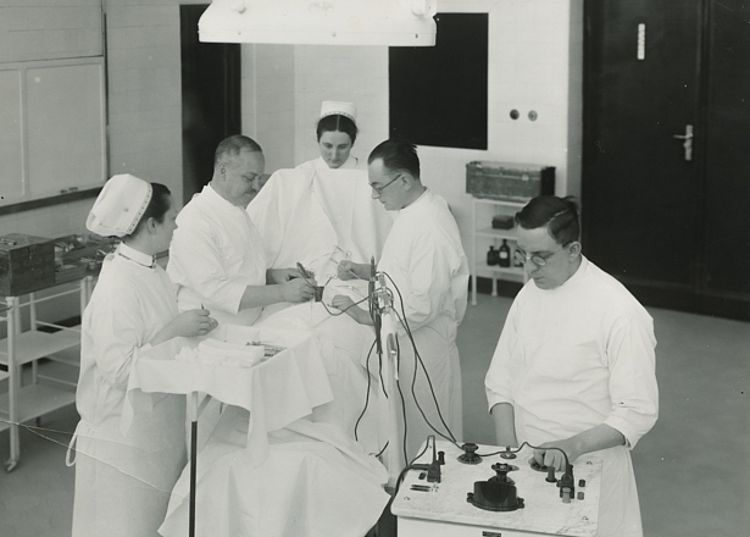 Emil Heymann bei einer Hirnoperation mit dem von ihm konzipierten Hochfrequenzgerät im Augusta-Hospital, um 1930 (Gerhard Heymann / DRK) Emil Heymann bei einer Hirnoperation mit dem von ihm konzipierten Hochfrequenzgerät im Augusta-Hospital, um 1930 (Gerhard Heymann / DRK)
