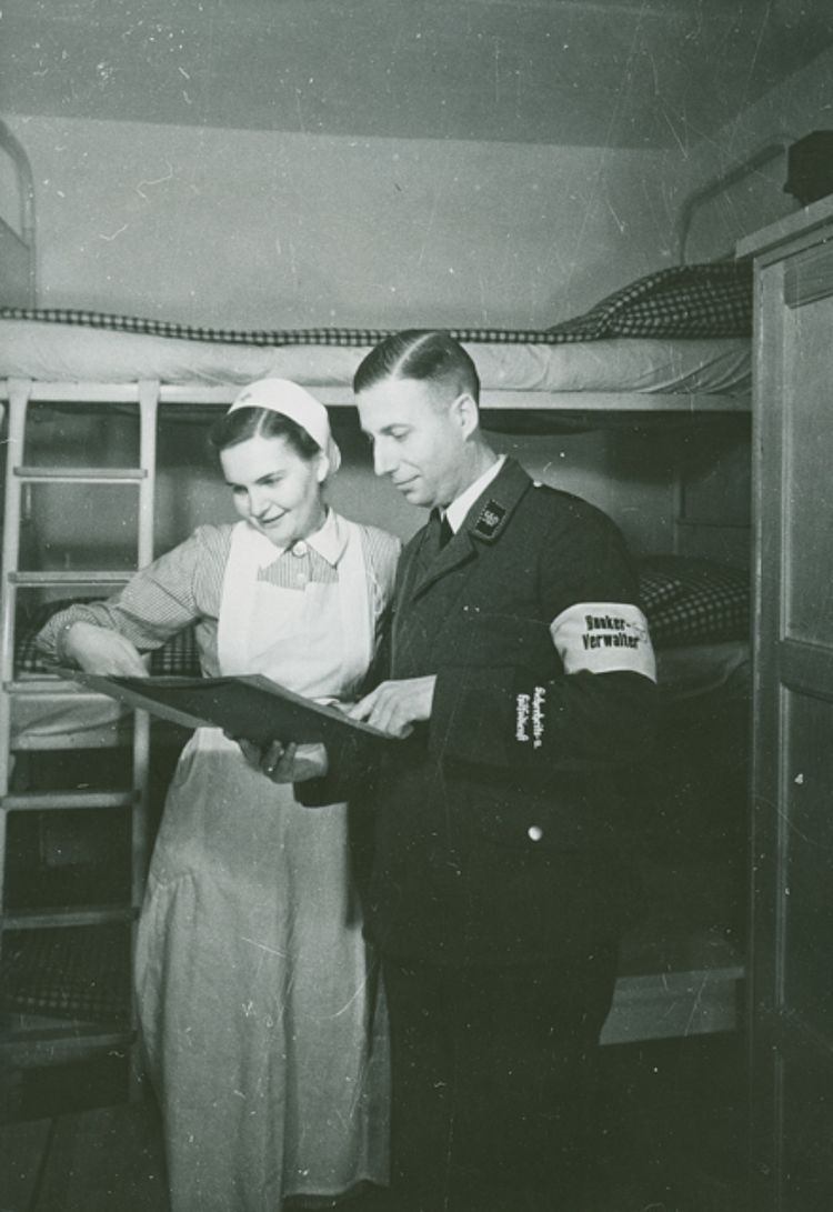 Eine DRK-Helferin und der Bunkerverwalter des Luftschutzbunkers in Berlin-Tempelhof prüfen die Liste mit den Namen der Anwesenden, 1941 (Stenner / DRK) Eine DRK-Helferin und der Bunkerverwalter des Luftschutzbunkers in Berlin-Tempelhof prüfen die Liste mit den Namen der Anwesenden, 1941 (Stenner / DRK)